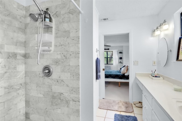 bathroom with a tile shower, vanity, and tile patterned floors