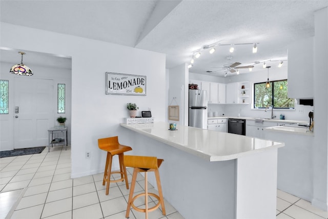 kitchen with white cabinetry, stainless steel refrigerator, ceiling fan, a breakfast bar area, and kitchen peninsula