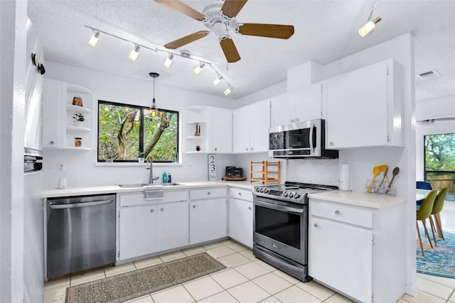 kitchen featuring stainless steel appliances, decorative light fixtures, sink, white cabinets, and light tile patterned flooring