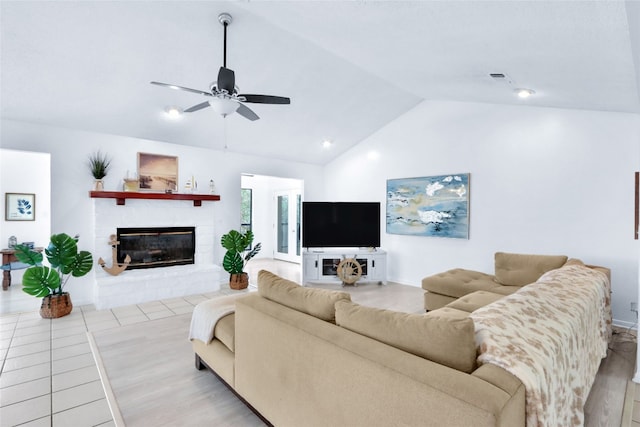 living room featuring ceiling fan, vaulted ceiling, light hardwood / wood-style flooring, and a fireplace