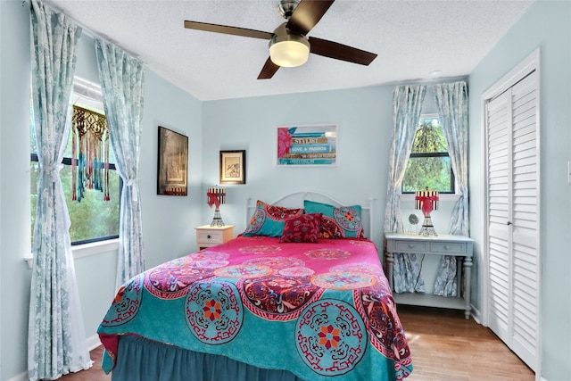 bedroom featuring a closet, ceiling fan, hardwood / wood-style floors, and multiple windows