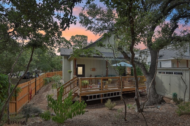 back house at dusk featuring a wooden deck