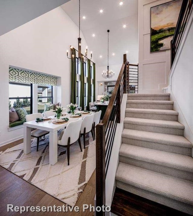 dining area with dark hardwood / wood-style floors, high vaulted ceiling, and a notable chandelier