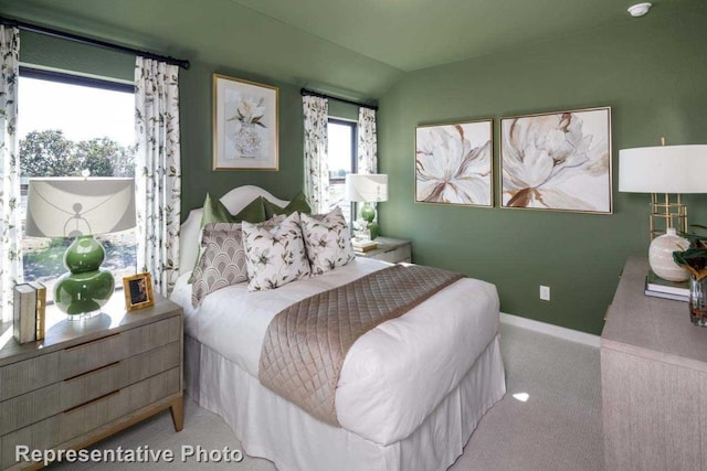 bedroom with carpet, vaulted ceiling, and multiple windows