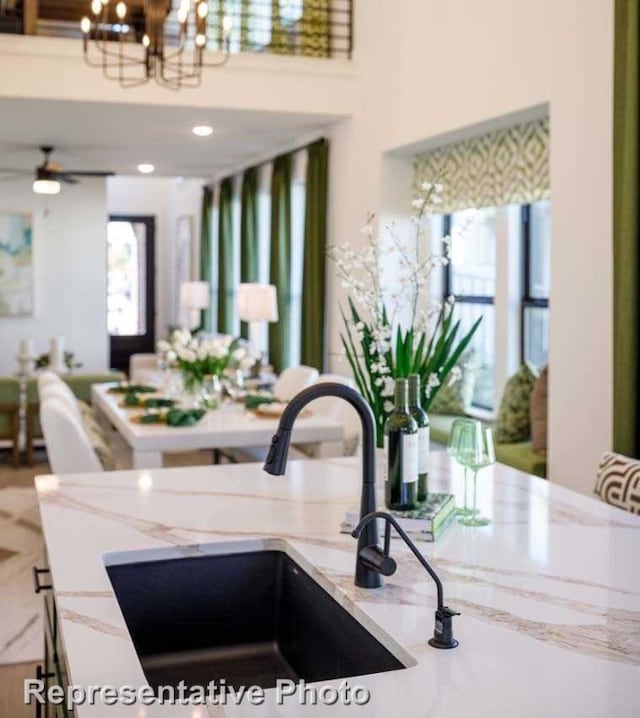 interior space with ceiling fan with notable chandelier, sink, and light stone counters