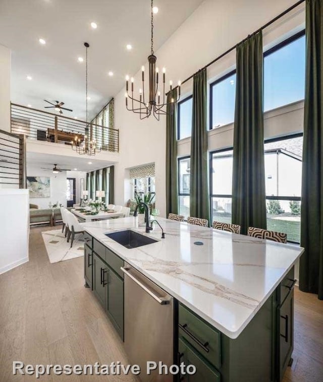 kitchen featuring ceiling fan with notable chandelier, stainless steel dishwasher, an island with sink, and plenty of natural light