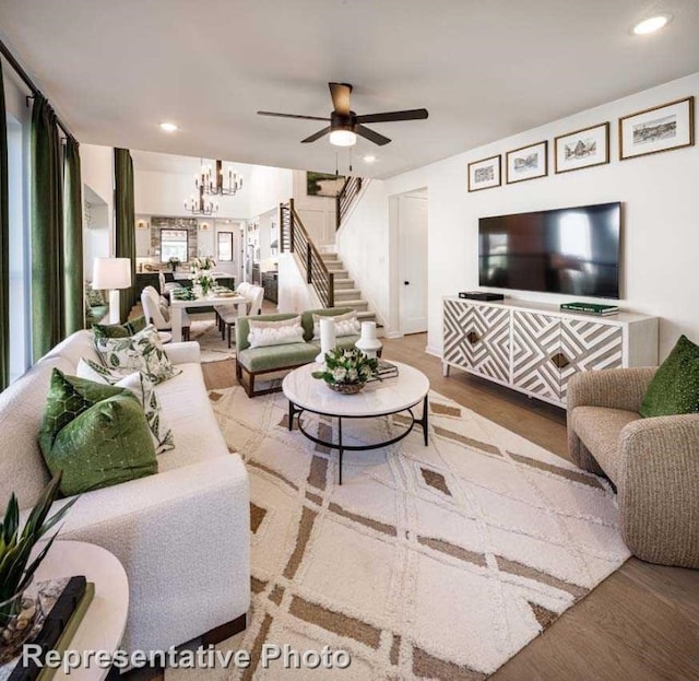 living room with ceiling fan with notable chandelier and hardwood / wood-style floors