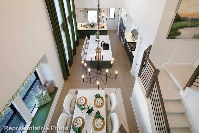 dining room with an inviting chandelier, a towering ceiling, and hardwood / wood-style flooring