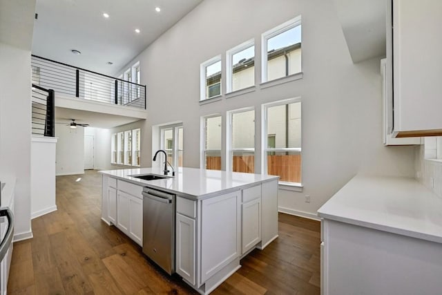 kitchen with sink, dark wood-type flooring, a kitchen island with sink, white cabinets, and stainless steel dishwasher