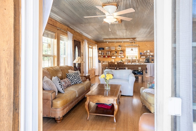 living room with wood walls, ceiling fan, hardwood / wood-style floors, and track lighting