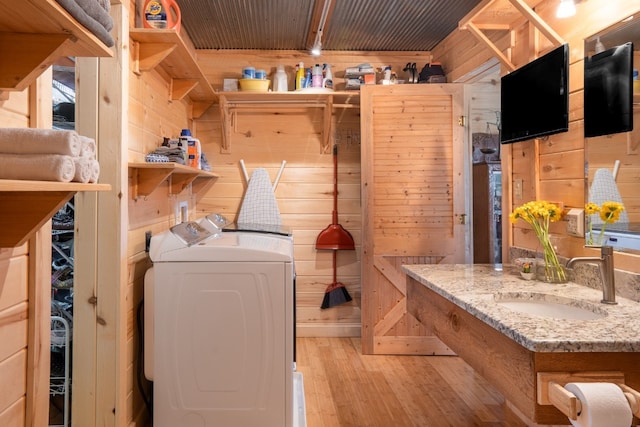 laundry room featuring sink, washing machine and dryer, light wood-type flooring, wooden walls, and wood ceiling