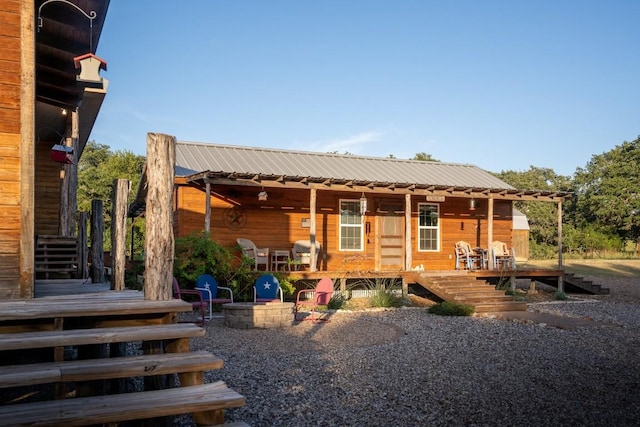 rear view of house with an outdoor fire pit and metal roof