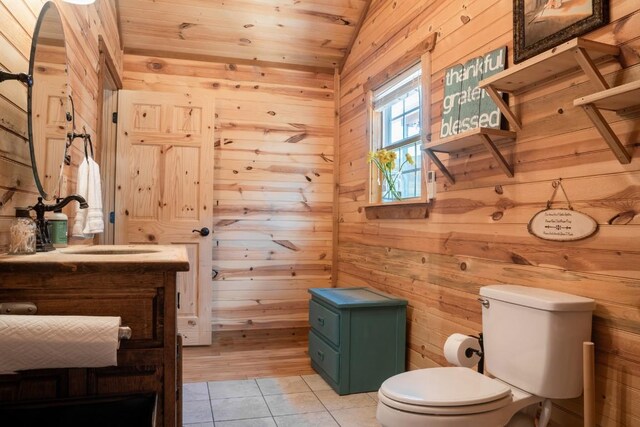 bathroom with tile patterned floors, vaulted ceiling, wood walls, and toilet