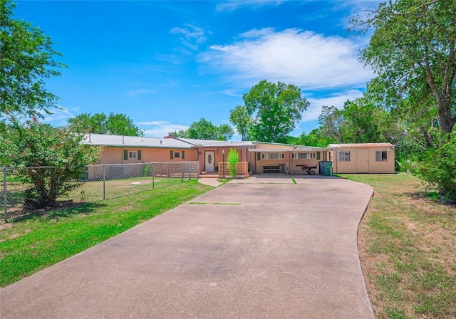 manufactured / mobile home with a fenced front yard, a front yard, an outbuilding, and driveway