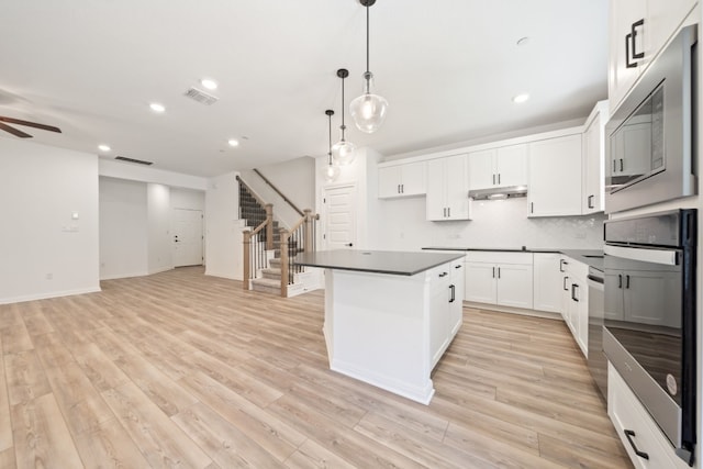 kitchen with pendant lighting, a center island, white cabinetry, and light hardwood / wood-style flooring