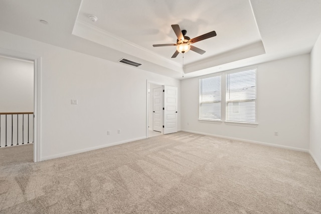 empty room with a tray ceiling, ceiling fan, and light colored carpet