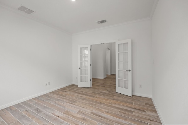 unfurnished bedroom featuring light wood finished floors, visible vents, ornamental molding, and french doors