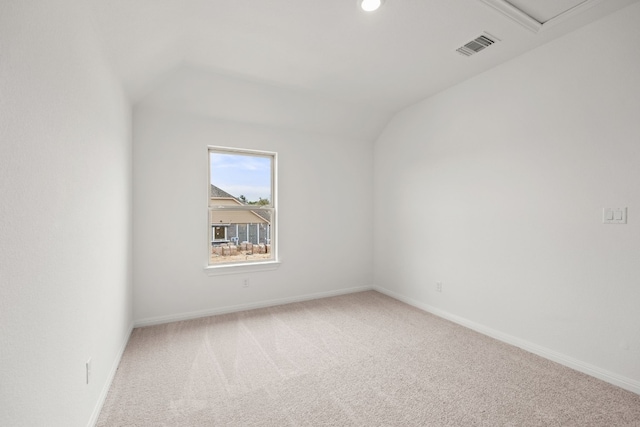 carpeted empty room with visible vents, vaulted ceiling, and baseboards