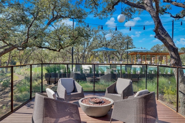 wooden terrace with a fire pit and a swimming pool