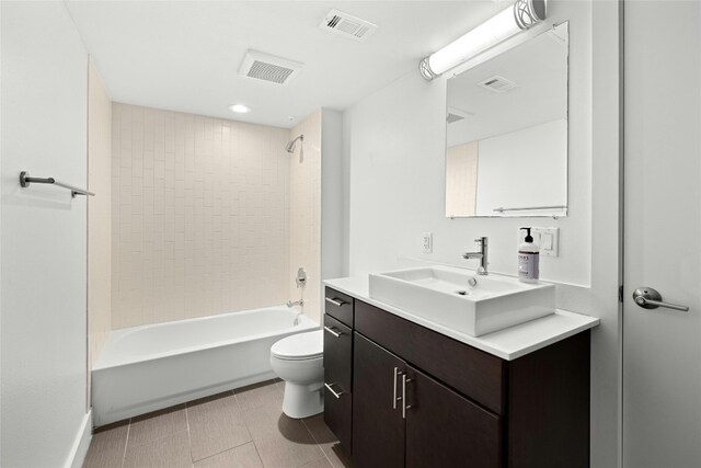 full bathroom with tile patterned floors, vanity, tiled shower / bath combo, and toilet