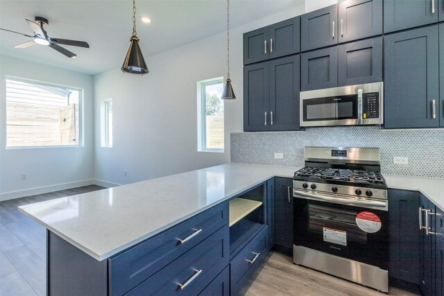 kitchen featuring hanging light fixtures, light wood-type flooring, decorative backsplash, stainless steel appliances, and kitchen peninsula