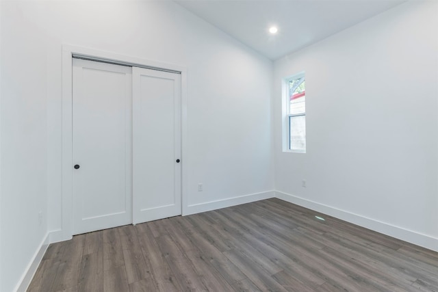 unfurnished bedroom featuring hardwood / wood-style floors, a closet, and lofted ceiling