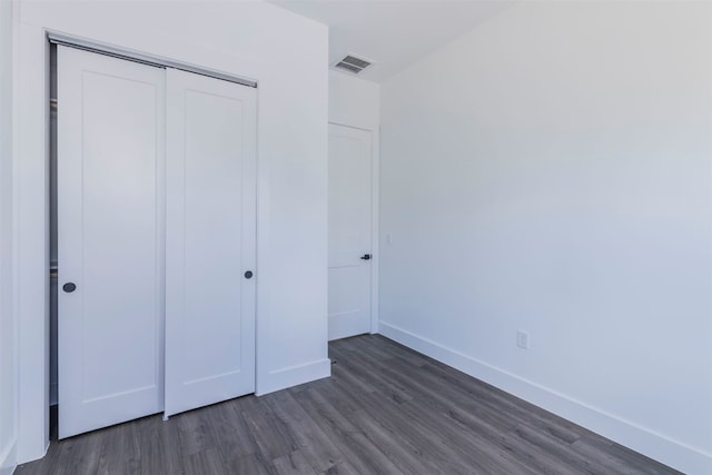 unfurnished bedroom with dark hardwood / wood-style flooring and a closet