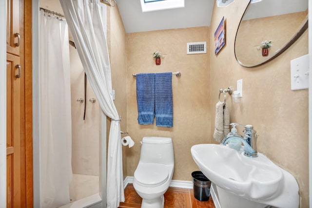 bathroom with toilet, a shower with curtain, a skylight, and sink