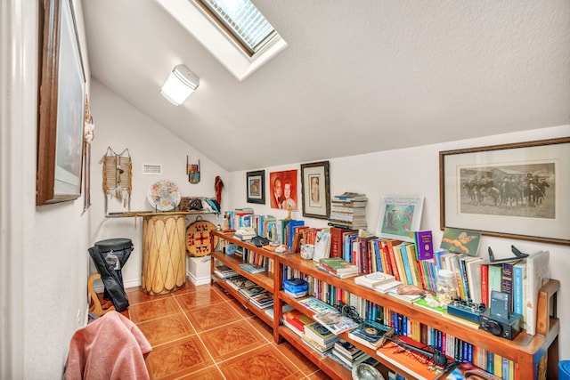 interior space featuring tile patterned flooring, a textured ceiling, and lofted ceiling with skylight