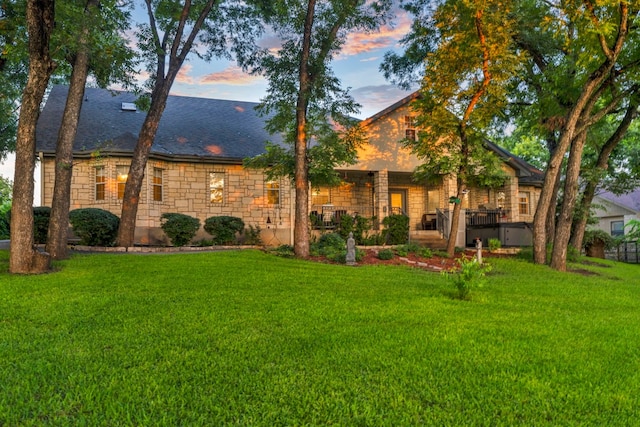 view of front facade featuring a lawn and a wooden deck