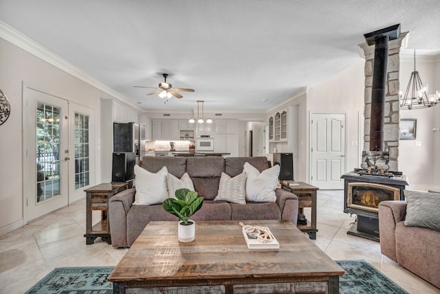 tiled living room with a wood stove, french doors, ceiling fan, and crown molding