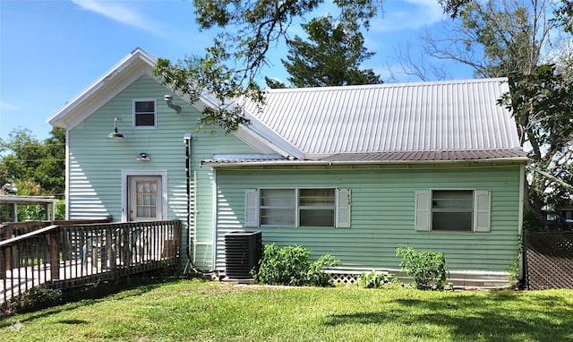 back of house with central air condition unit and a yard