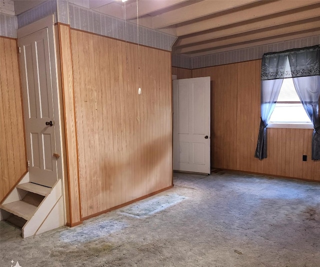 interior space featuring beam ceiling, carpet, and wooden walls