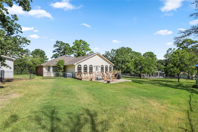 back of property with a deck, a lawn, and a patio