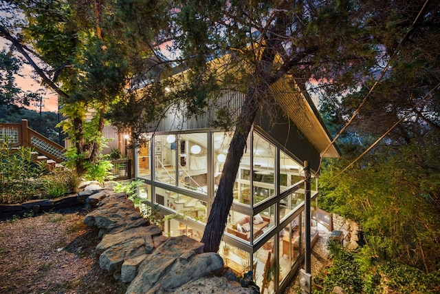 back house at dusk with a sunroom