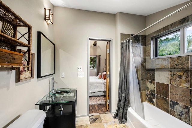 full bathroom with stone tile floors, ensuite bathroom, toilet, shower / bathtub combination with curtain, and vanity