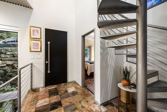foyer with a wealth of natural light, stone finish floor, and a towering ceiling