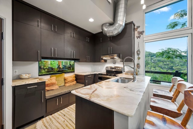 kitchen with sink, a kitchen island with sink, and stainless steel range with electric stovetop