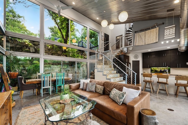 living room featuring stairs, a high ceiling, and concrete floors