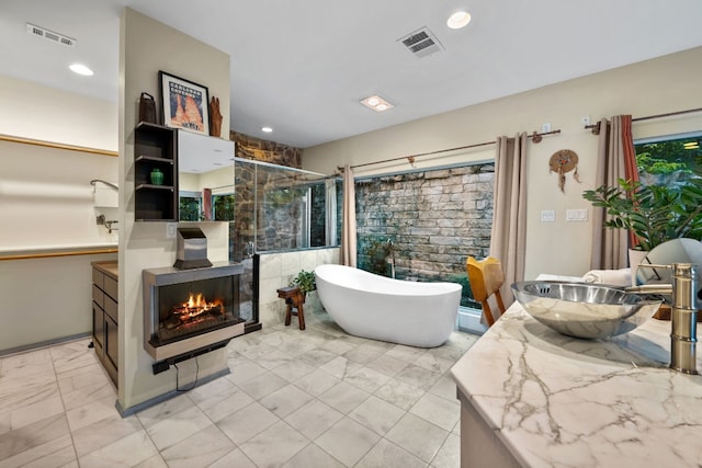 3025 Geronimo Trl, Austin, TX 78734 - bathroom with vanity, marble look tiles, a freestanding bath, a shower stall, and recessed lighting