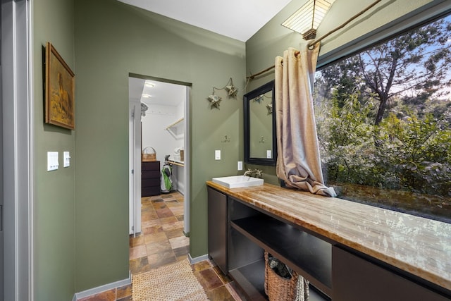bathroom with stone tile floors, vanity, and baseboards