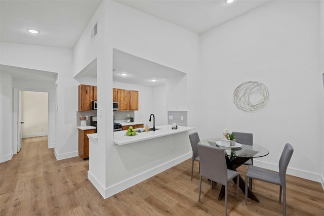 kitchen with kitchen peninsula, light hardwood / wood-style floors, sink, and appliances with stainless steel finishes