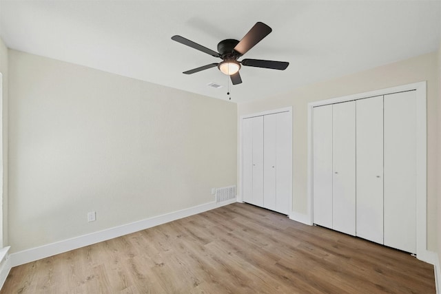 unfurnished bedroom featuring light hardwood / wood-style flooring, ceiling fan, and two closets