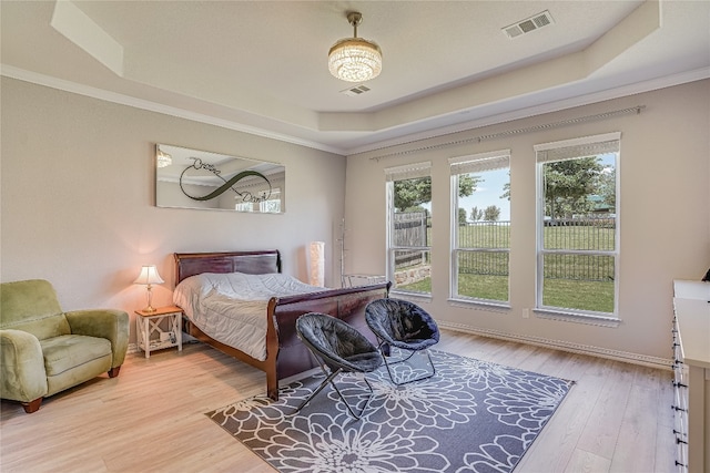 bedroom with a raised ceiling, crown molding, and light hardwood / wood-style flooring