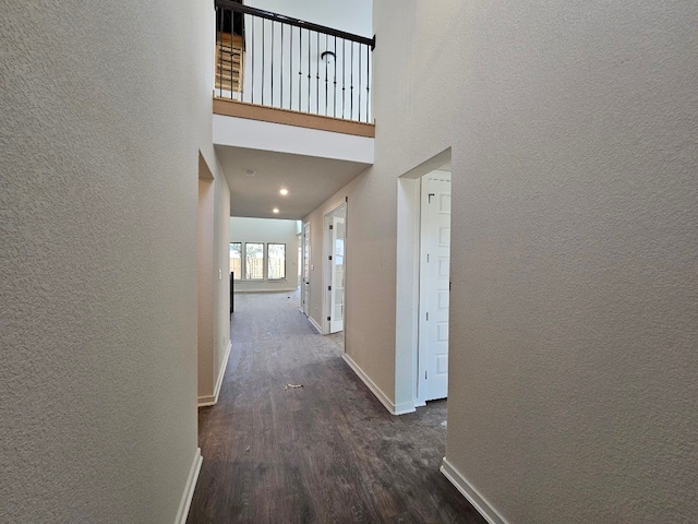 hallway featuring a towering ceiling and dark hardwood / wood-style floors