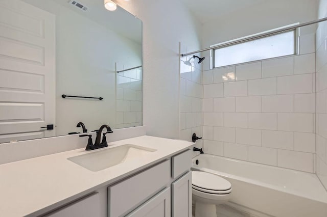 bathroom with visible vents, toilet, vanity, and shower / tub combination