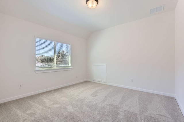 spare room with light carpet, visible vents, baseboards, and vaulted ceiling