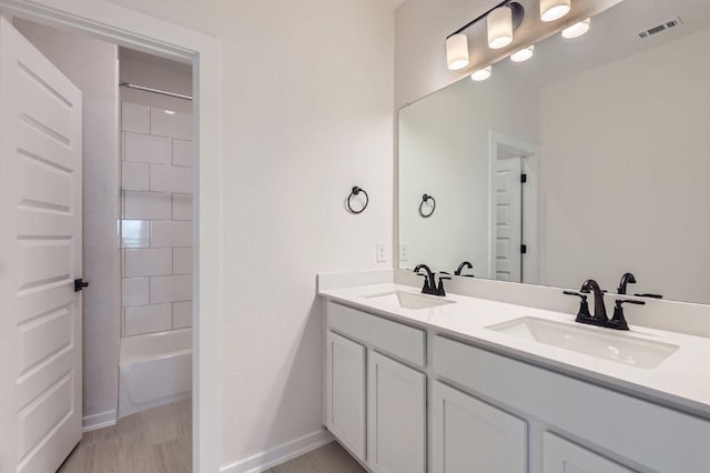 full bathroom with a sink, visible vents, baseboards, and double vanity