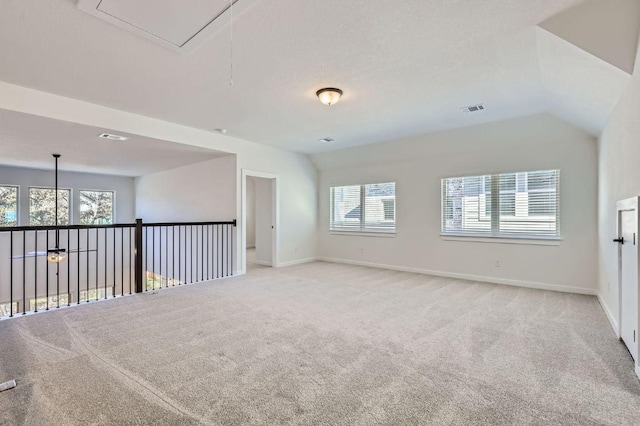 unfurnished room featuring visible vents, light colored carpet, attic access, and vaulted ceiling