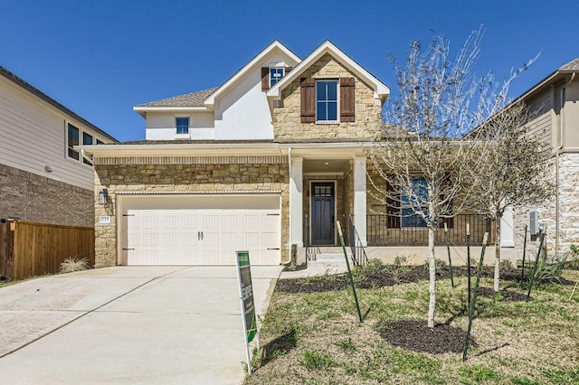 traditional home featuring a garage, stone siding, concrete driveway, and fence